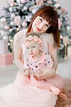 Christmas and Happy New Year Holidays. Family, mother and child concept. Happy mom and her cute baby girl in pink