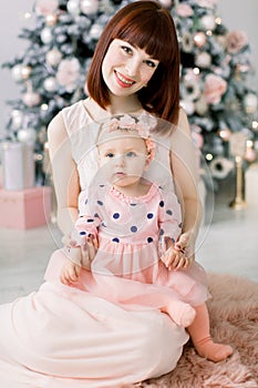 Christmas and Happy New Year Holidays. Family, mother and child concept. Happy mom and her cute baby girl in pink