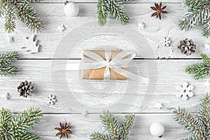 Christmas or Happy New Year present in frame made of fir tree branches, holiday decorations on white wooden background