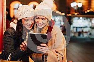 Christmas happy people digital tablet concept. Happy women friends enjoying shopping in the city