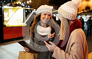 Christmas happy people digital tablet concept. Happy women friends enjoying shopping in the city