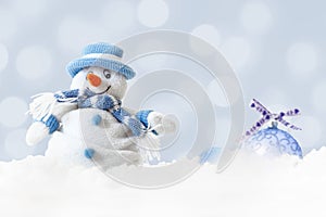 Funny blue snowman on xmas lights bokeh background, white snowflakes, merry Christmas and happy new year card concept