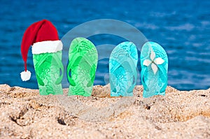 Christmas hat on flip flops in the sand