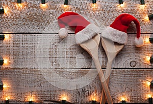 Christmas hats on wooden spoons framed by decorative lights