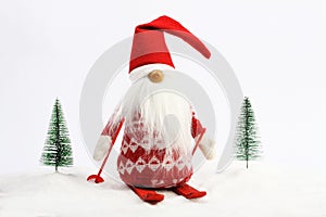 Christmas helper (elf) skiing on snow next two snowy trees Red and white colors