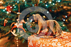 Christmas hobbyhorse made of wood on a present near a Christmas tree