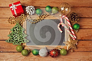 Christmas holiday background with blank chalkboard on wooden table and Christmas decorations.