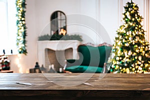 Christmas holiday background with empty rustic table and the bokeh of the living room with the Christmas tree, sofa and fireplace