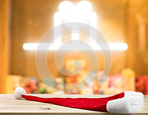 Christmas holiday background with empty wooden table top and christmas hat  over festive bokeh light xmas gift box