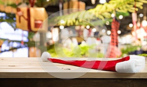 Christmas holiday background with empty wooden table top and christmas hat  over festive bokeh light xmas gift box