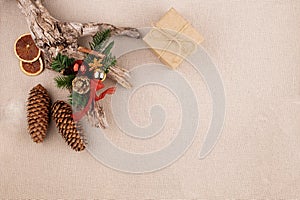 Christmas holiday background with fir tree decorated with pine cone, cinnamon sticks and gift wrapped in kraft paper, dried