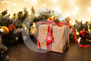 Christmas holiday background. Gifts with a red ribbon, Santa`s cap and decor under a Christmas tree on a wooden board. Close up.