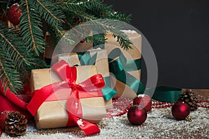 Christmas holiday background. Gifts with a red ribbon, Santa`s hat and decor under a Christmas tree on a wooden board.