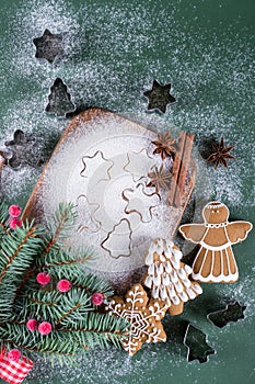 Christmas and holiday baking background. Fir trees with decoration, flour, spices and cookies molds on a cutting board.