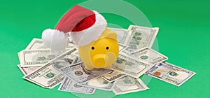 Christmas holiday bonus and expenses. Piggy bank with Santa hat on US dollars money