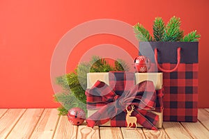 Christmas holiday celebration concept with gift box, paper gift bag and pine tree branches on wooden table