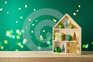 Christmas holiday concept with toy house and  decoration  on wooden shelf over green background