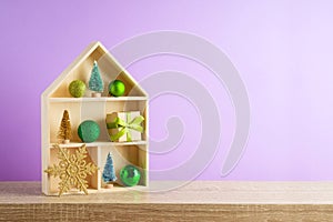 Christmas holiday concept with toy house and  decoration  on wooden shelf over violet background
