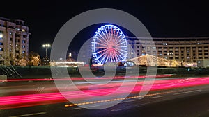 Christmas holiday ferris wheel in Bucharest, Romania, at night, with car light trails