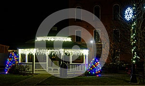 Christmas or Holiday lights at night on white gazebo with two Christmas trees at night