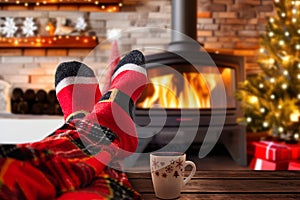 Christmas holiday mood relaxing in front of cozy fireplace and enjoying cup of hot chocolate