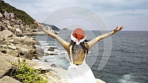 Christmas holiday santa hat with woman  in white dress which she feeling a freedom relaxing on paradise beach island