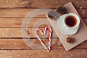 Christmas holiday tea cup on old books with love shaped candy on wooden table with copy space