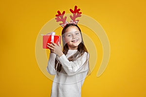 Christmas, holidays and childhood. Happy girl with horns listens gift