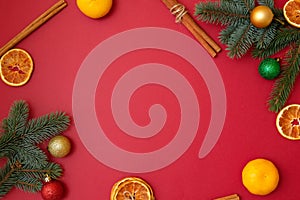 Christmas holidays composition on red background with copy space for your text. Xmas tree branches in the corners, dried oranges,
