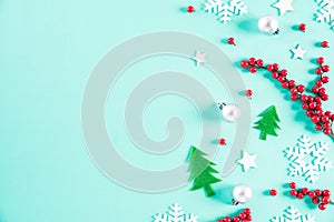 Christmas holidays composition Top view of Christmas tree decoration and red berries on green pastel background with copy space