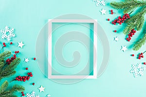 Christmas holidays composition Top view of white picture frame with Christmas tree decoration and red berries on green pastel