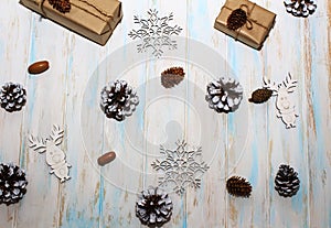 Christmas holidays composition on white wooden background. Craft boxes of gifts, wooden deer and snowflakes, fir cones, pine cones