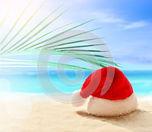 Christmas holidays concept. Santa claus hat on summer sand beach