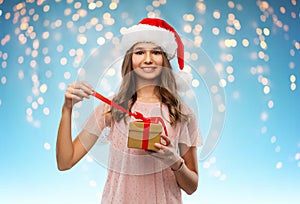 Teenage girl in santa hat opening christmas gift
