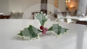 Christmas holly leaf and berry on white cafe table