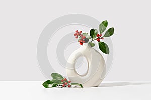 Christmas holly with red berries in white vase. Winter natural decoration.