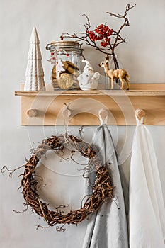 Christmas home decor composition on a wooden shelf in the interior of a scandinavian style room with homemade  wreath