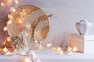 Christmas home decoration with burning lights on white wooden background.