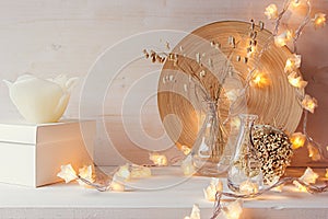 Christmas home decoration with burning lights on white wooden background.