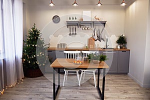Christmas home interior. Modern kitchen. On the table is a composition of fir branches and candles