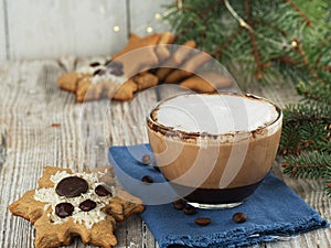 Christmas homemade gingerbread cookies, and a glass cup with hot cappuccino coffee. Close-up. Wooden vintage background, near the