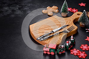 Christmas homemade gingerbread cookies, spices and cutting board on dark background