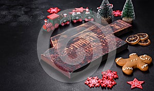 Christmas homemade gingerbread cookies, spices and cutting board on dark background