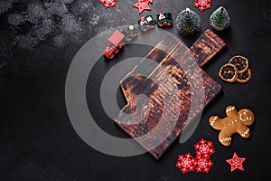 Christmas homemade gingerbread cookies, spices and cutting board on dark background