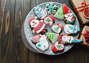 Christmas homemade gingerbread cookies, spices on the plate on dark wooden background among Christmas presents,