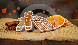 Christmas homemade gingerbread cookies on wooden table, slices of dry orange and colored lights on background