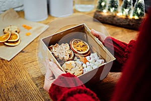 Christmas Homemade Sweet Hampers in female hands. Woman hsnds holding Christmas Sweet Gift Box. Festive treats Gift