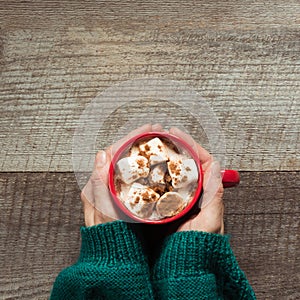 Christmas hot chocolate with marshmallows in hand on the wooden background. Top view with copy space.