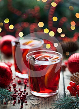 Christmas hot cranberry tea, orange pomegranate punch or mulled wine in a rustic wooden table. Closeup.