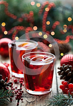 Christmas hot cranberry tea, orange pomegranate punch or mulled wine in a wooden table. Closeup. Winter tree decorations